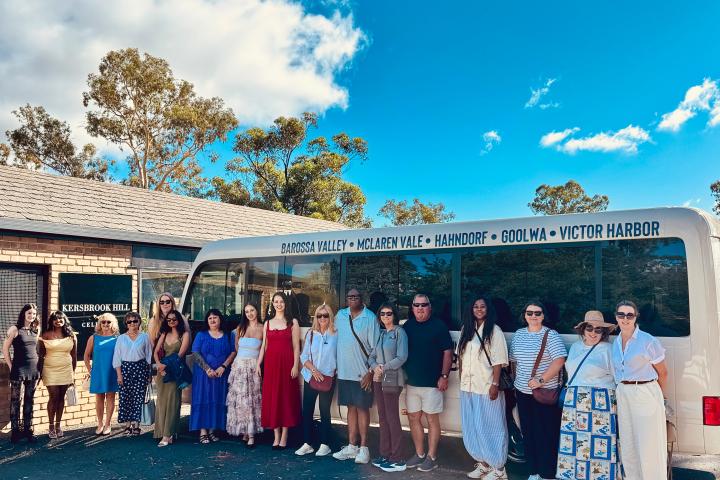 Group of people standing in front of a tour bus with scenic background.