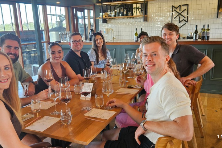 Group of people smiling at a restaurant table with wine glasses.