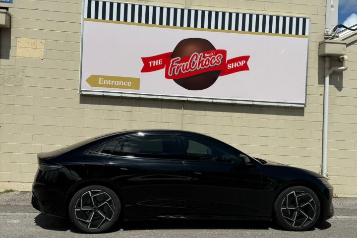 Black car parked in front of a beige building with a 'FruChocs Shop' sign.