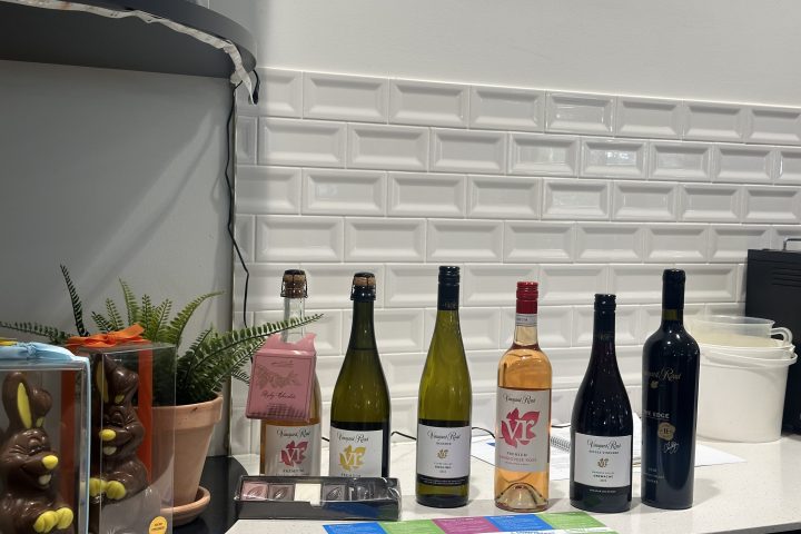 Six wine bottles and chocolate bunnies on a counter with a tiled backsplash.