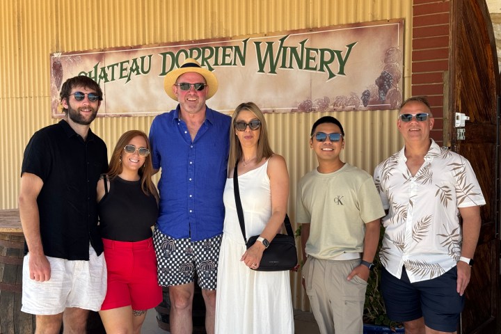 Group of six people posing in front of Chateau Dorrien Winery sign.