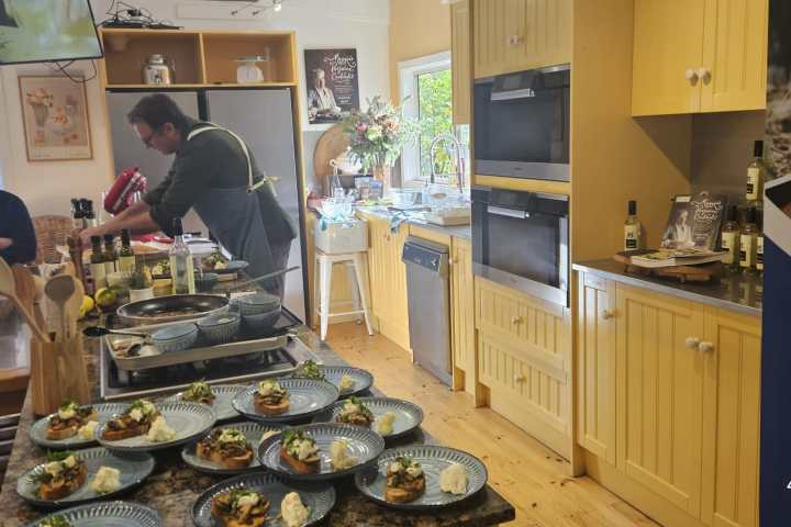 Chef cooking in a kitchen with plated meals and a dining area.
