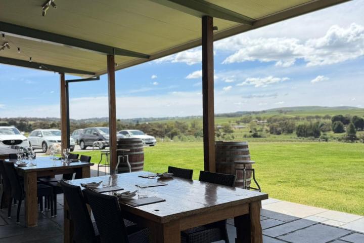Outdoor dining area with wooden tables, chairs, and a scenic landscape view.