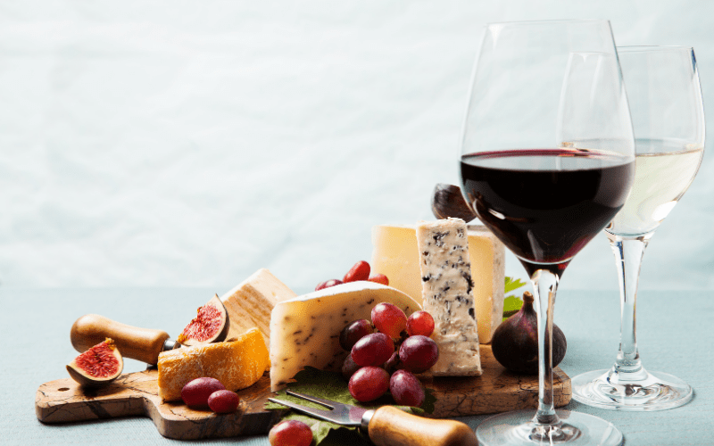 cheese and wine a plate of food and a glass of wine
