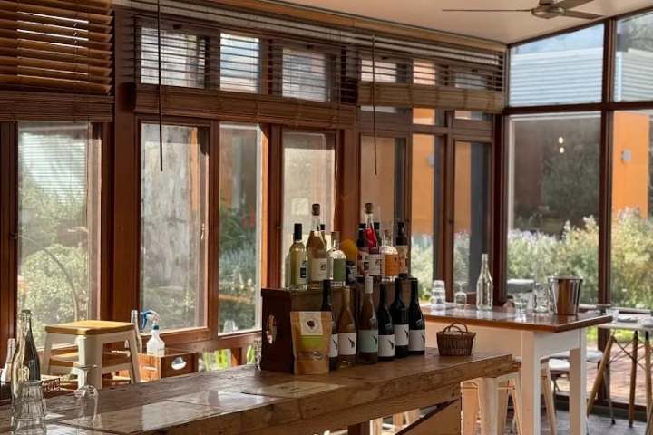 Cozy café interior with wooden tables and sunlight through large windows.