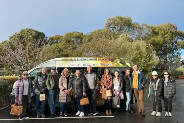 Group posing in front of a tour van on a cloudy day.