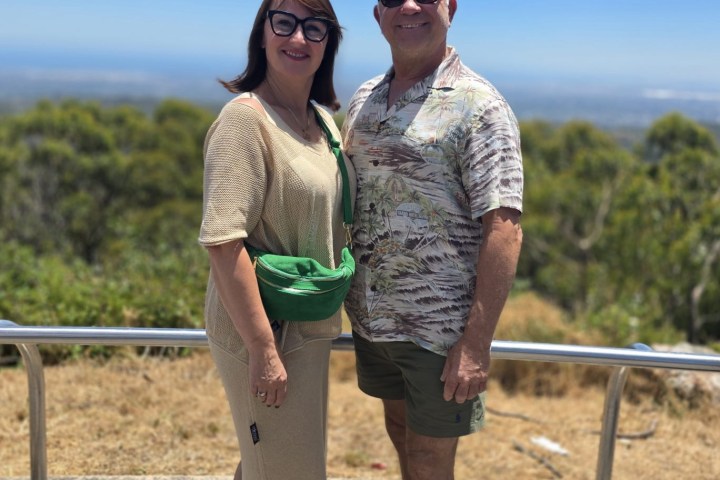 Couple posing in casual attire with scenic view.
