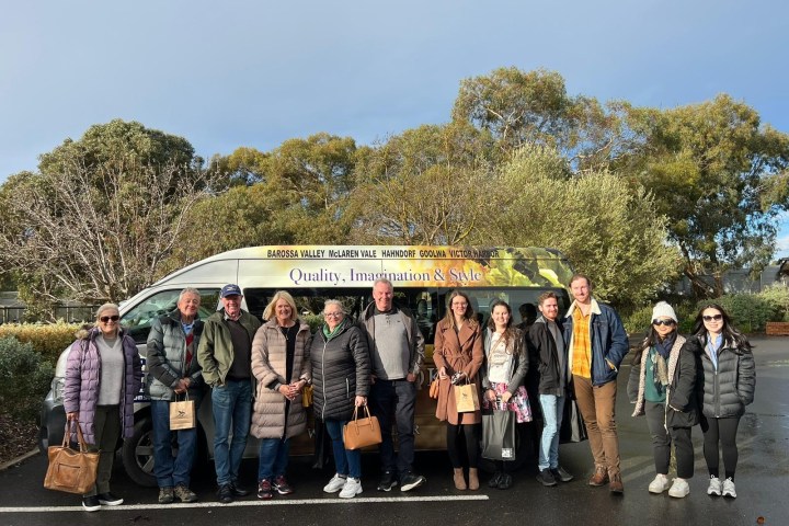 Group of people posing in front of a van on a cloudy day.